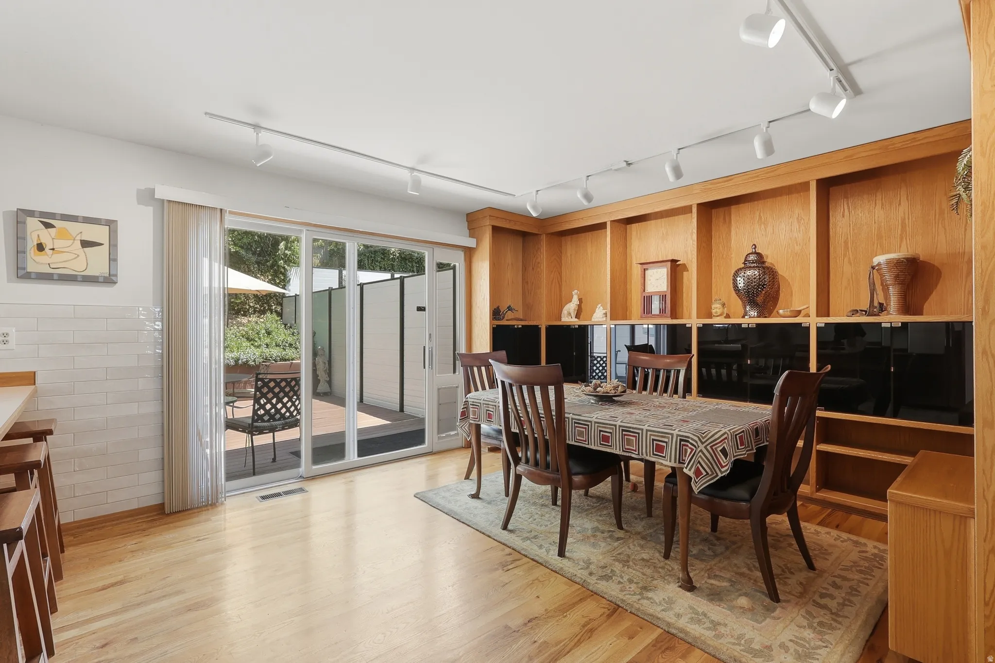 Dining area featuring built-in wood shelving with black cabinet bases, wood-finish flooring, and track lighting