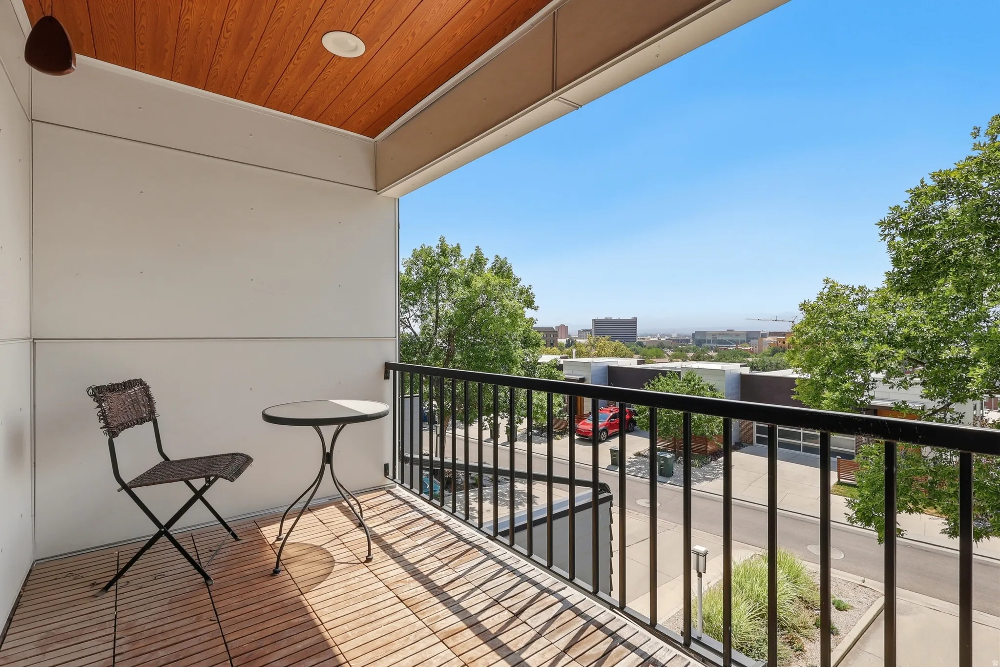 Private covered balcony with city/valley views, wood-finish flooring and a black metal railing