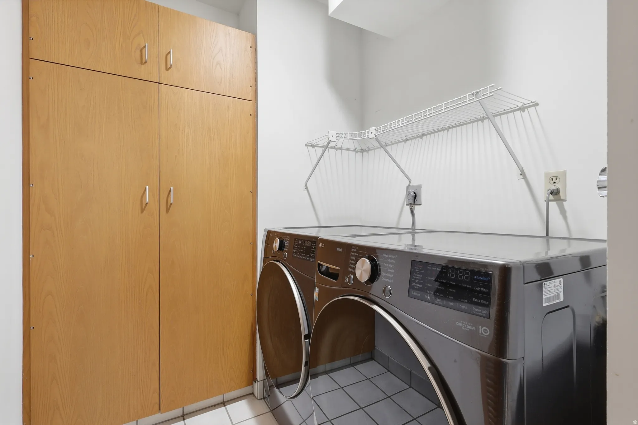 Laundry area featuring ample built-in cabinetry, tiled flooring, and a wire drying rack