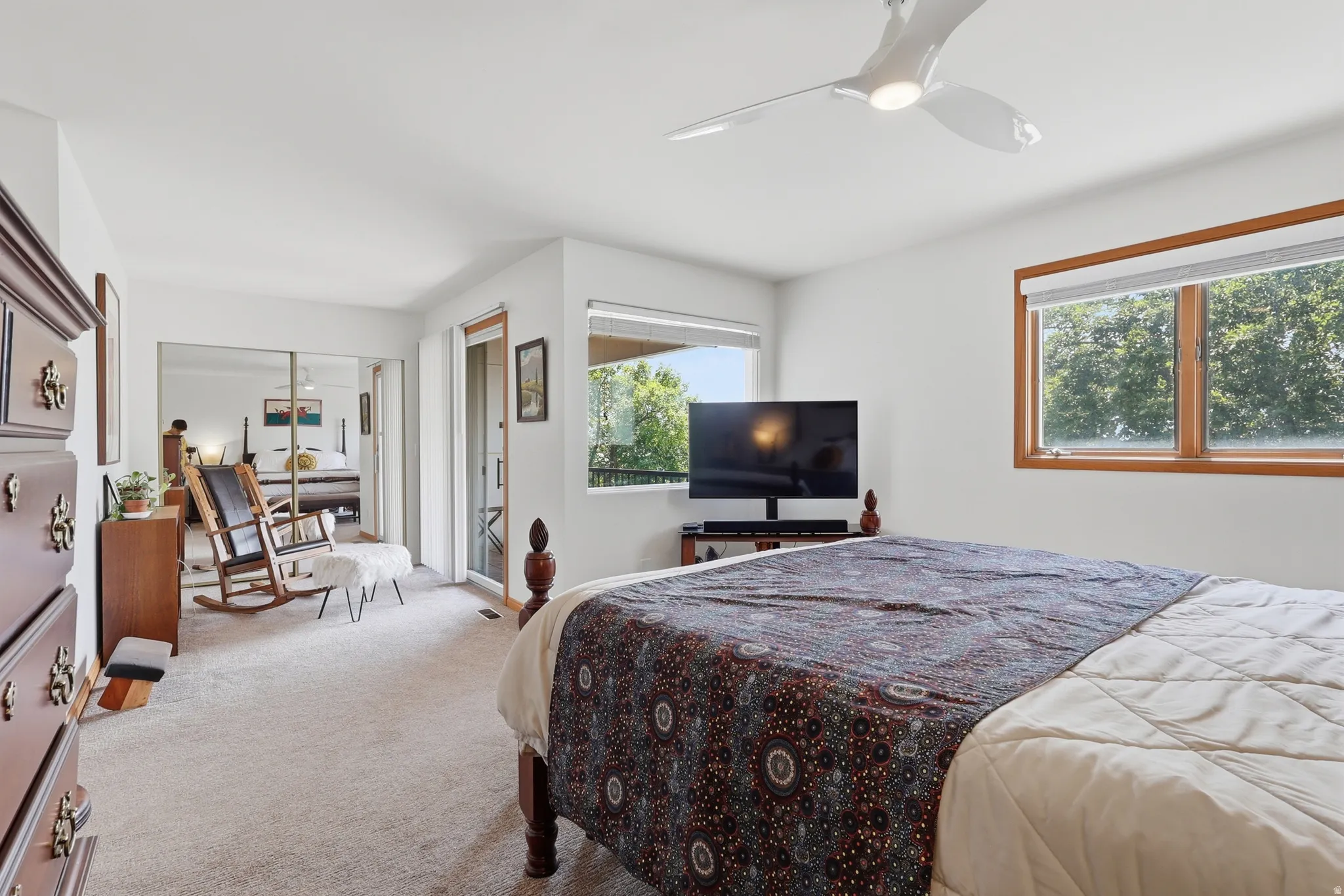 Primary suite featuring a ceiling fan, wood-framed windows, and a flex space with a sliding glass door leading to a private view deck.