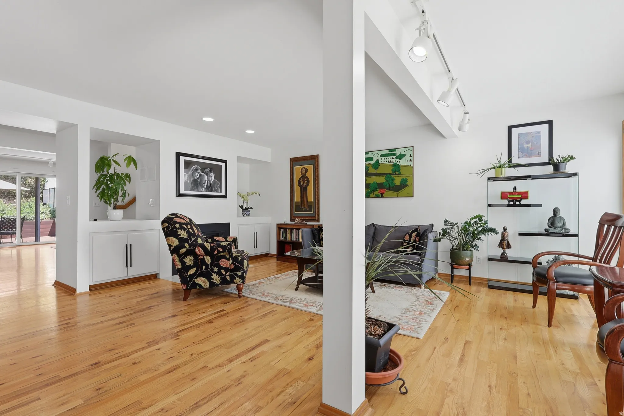 Hardwood flooring throughout a spacious living area featuring built-in cabinetry, recessed lighting, and track lighting