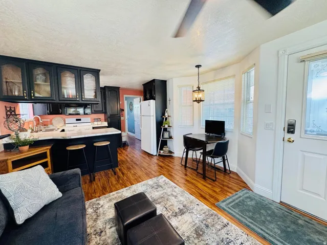 Open-concept living area featuring wood-finish flooring, a kitchen with dark cabinetry and light countertops, and a dining nook with bay windows