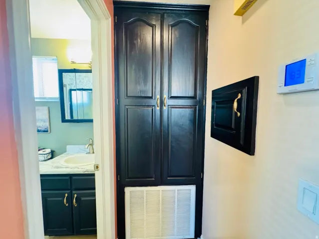 Built-in storage cabinet with black paneled doors and gold-toned hardware