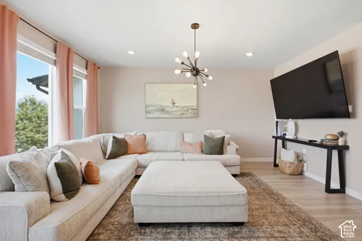 Spacious living area featuring light wood-finish flooring, a contemporary sputnik chandelier, recessed ceiling lighting, and large windows