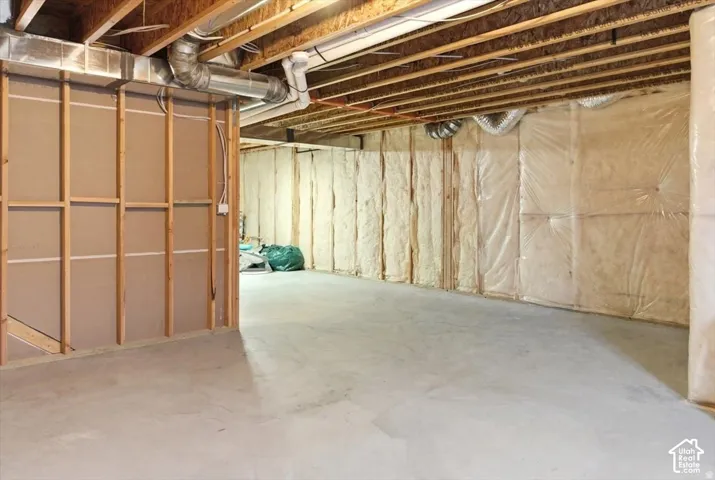 Unfinished basement featuring exposed wood joists, concrete flooring, and insulated perimeter walls