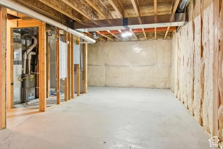 Unfinished basement space with exposed wooden joists and framing, insulated perimeter walls, concrete flooring, and visible HVAC ductwork