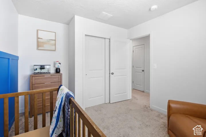 Spacious room featuring neutral carpeting, white interior doors, and a closet with bifold doors