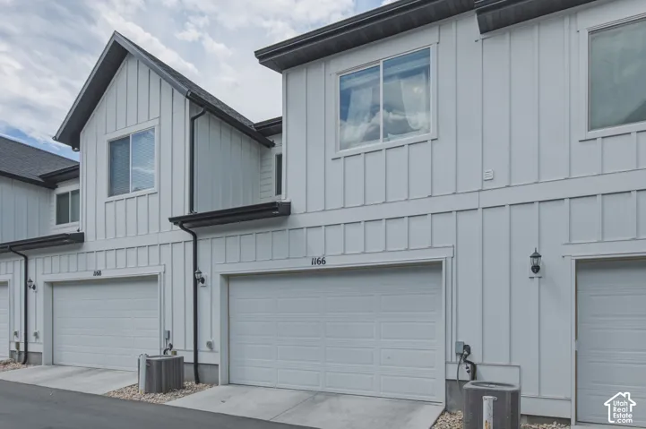 Contemporary townhome exterior featuring board and batten siding, dark trim, and individual garage doors