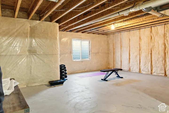 Unfinished lower level featuring exposed ceiling joists, concrete flooring, and insulated wall framing