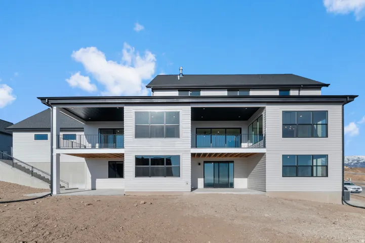 Contemporary multi-level exterior with light-colored horizontal siding, black-framed windows, and a black shingle roof