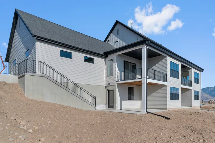 Contemporary multi-story exterior with light-colored siding, dark-framed windows, and a black shingle roof