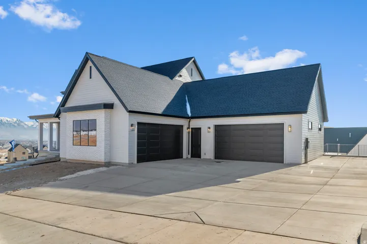 Modern exterior featuring white siding, a dark pitched roof, and two spacious garages with dark doors
