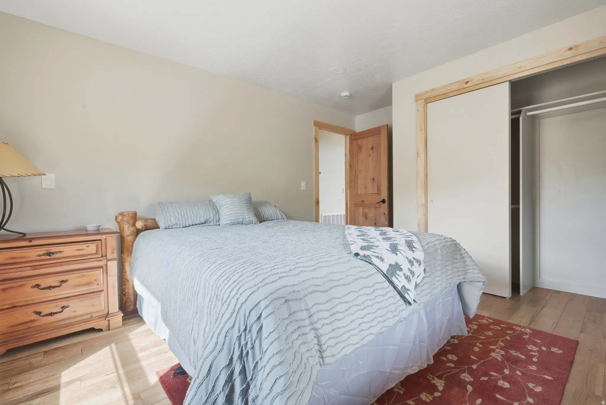 Room featuring wood-finish flooring, a wood-frame sliding closet door with natural wood trim, and a solid wood interior door with black hardware