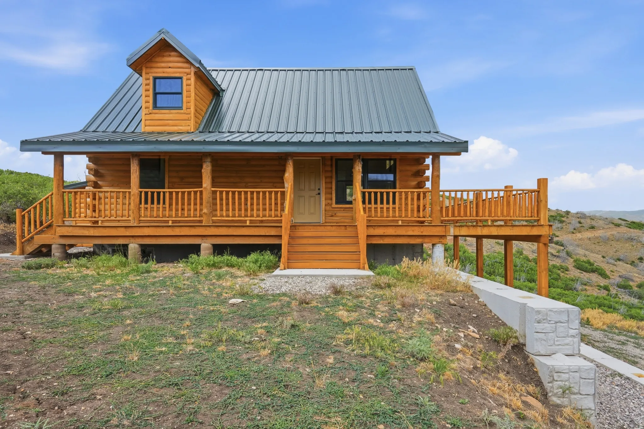 Log home featuring a covered front porch with wood railings and steps, a dormer window, and a metal roof