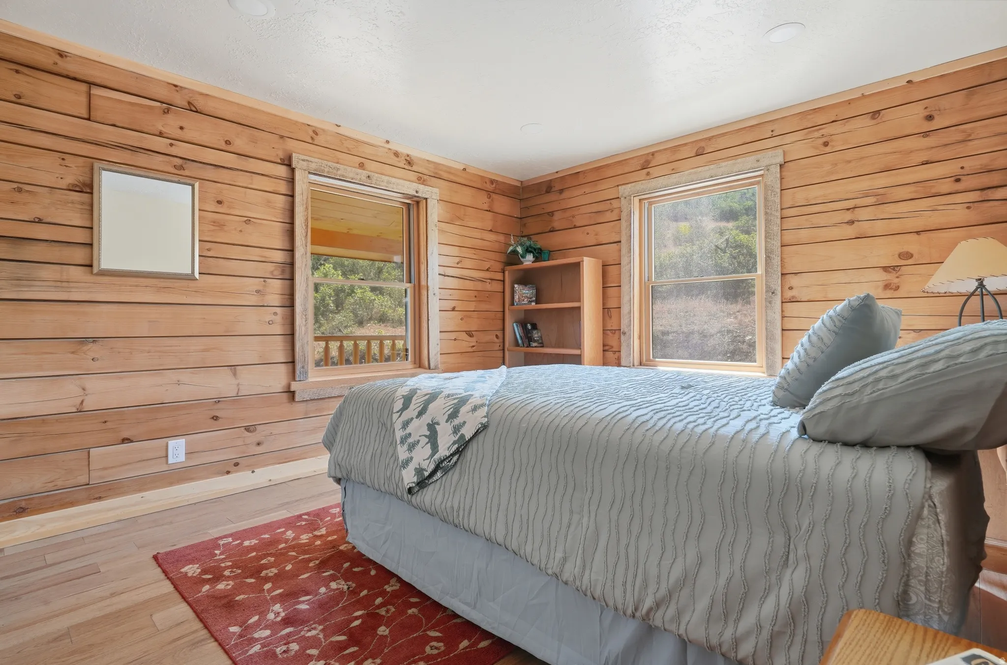 Wood-paneled room featuring natural light from two windows and light wood-finish flooring