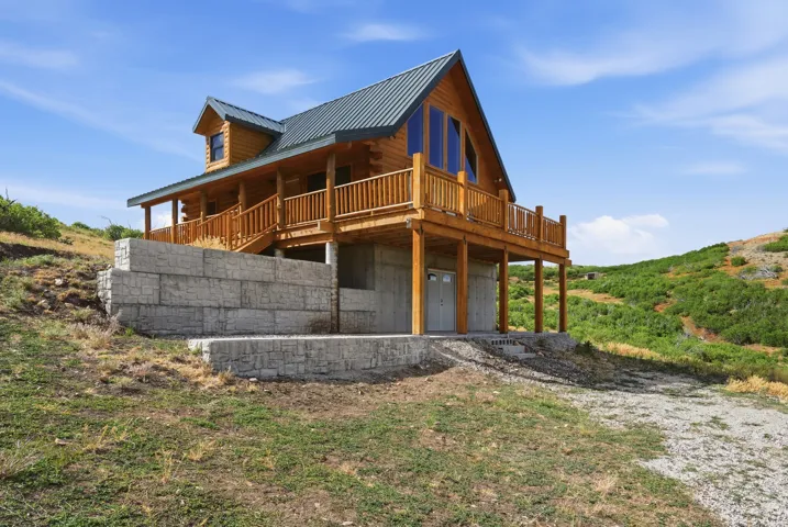 Log cabin exterior featuring a metal roof, dormer window, and an expansive deck with wood railing
