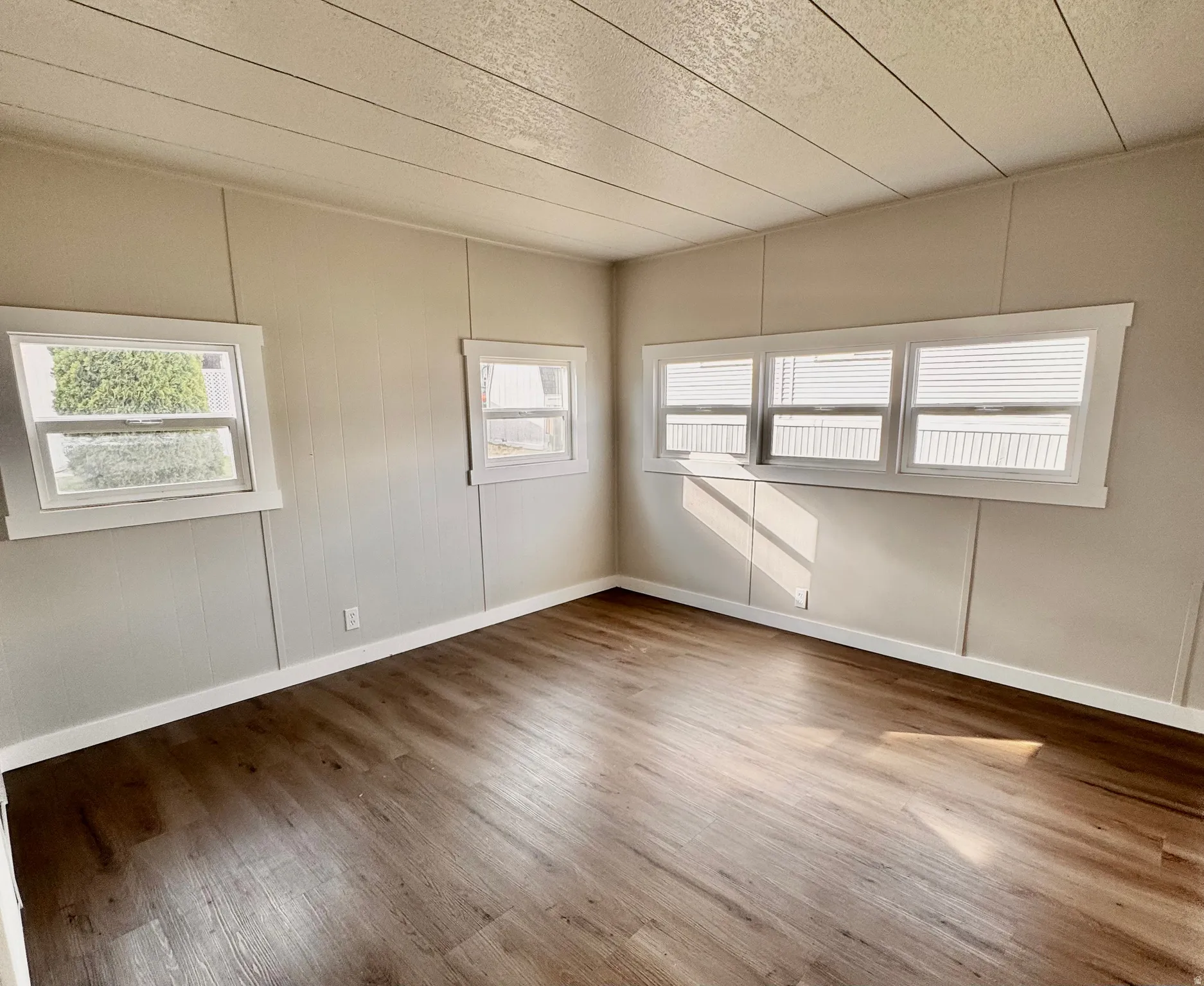 Spacious interior featuring wood-finish flooring, light-toned walls, multiple windows, and white trim