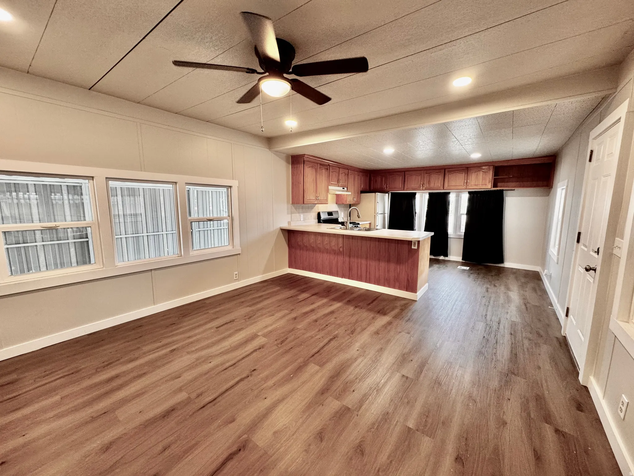 Open-concept living space featuring wood-finish flooring, recessed lighting, and a ceiling fan