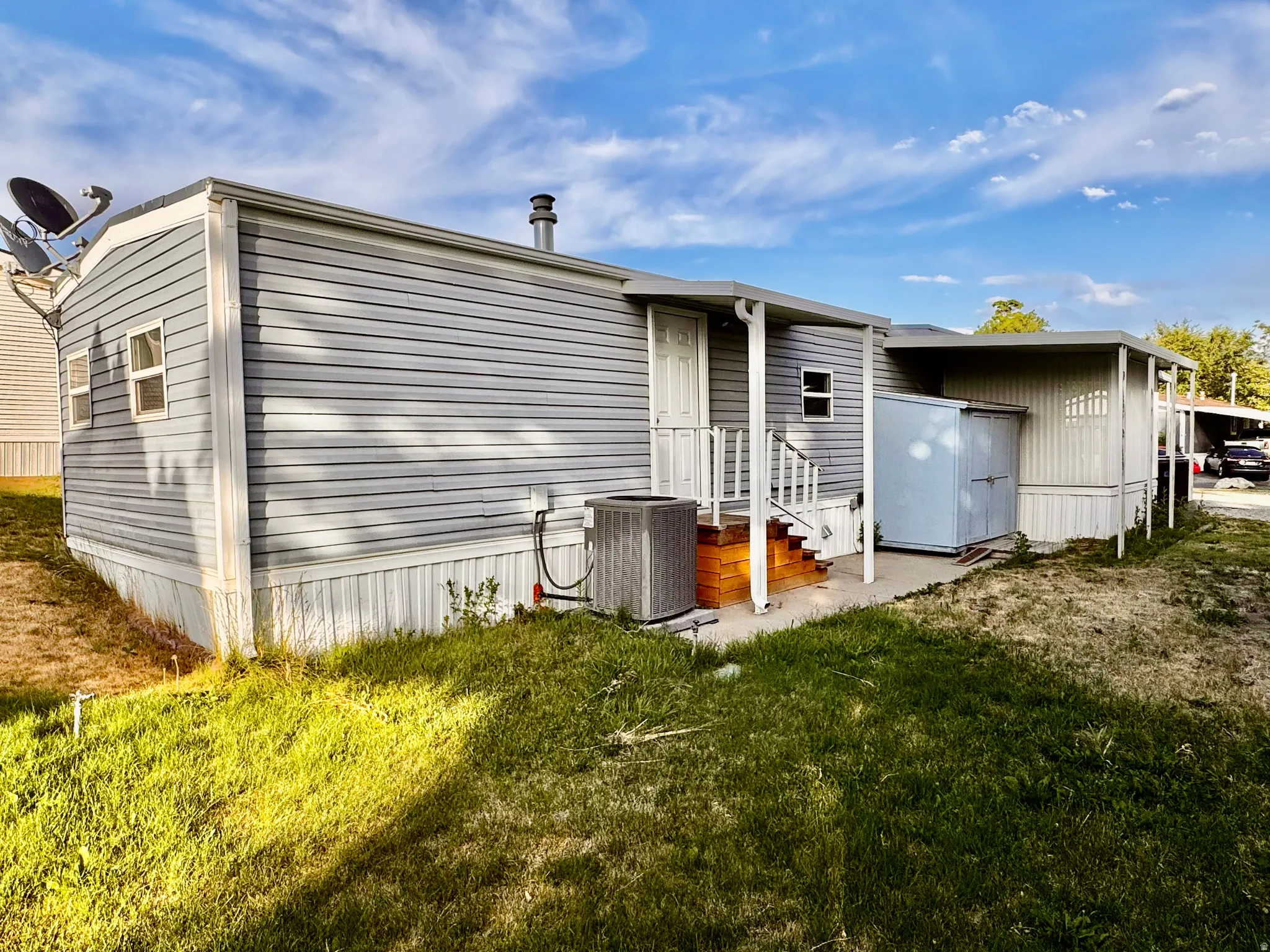 Exterior siding with a white trim, a covered porch, and an attached storage shed