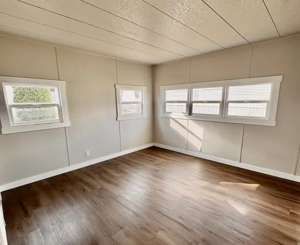 Spacious interior featuring wood-finish flooring, light-toned walls, multiple windows, and white trim