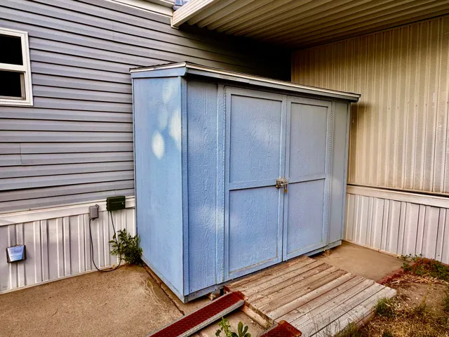 Freestanding shed with double doors and a wood plank ramp