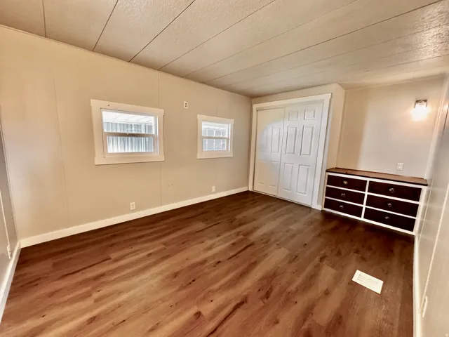 Spacious room featuring wood-finish flooring, light-toned walls, and white trim