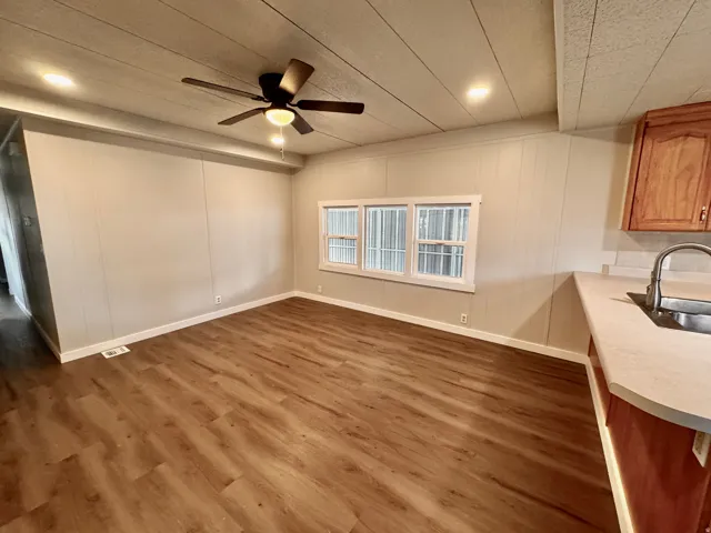 Open concept living area featuring wood-finish flooring, a ceiling fan with integrated lighting, recessed lighting, and a window with white trim