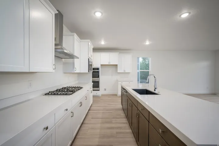 Modern kitchen featuring white shaker cabinetry, stainless steel appliances, a gas cooktop, and a spacious island with an undermount sink