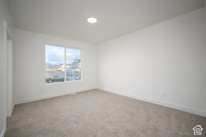 Light-filled interior space featuring a large window, neutral carpet, white walls, and a ceiling-mounted light fixture