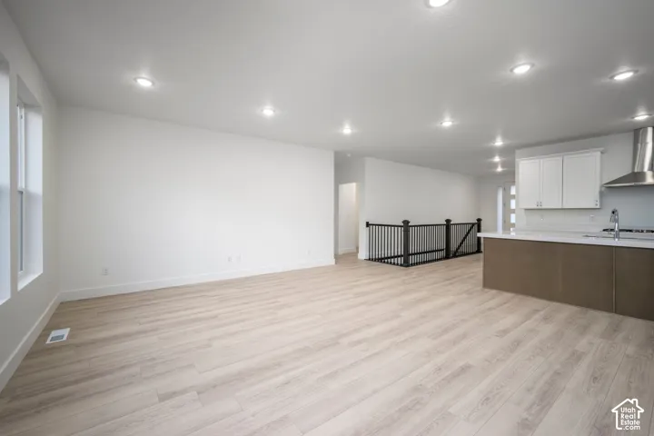 Expansive interior featuring wood-finish flooring, recessed lighting, and a kitchen island with integrated sink
