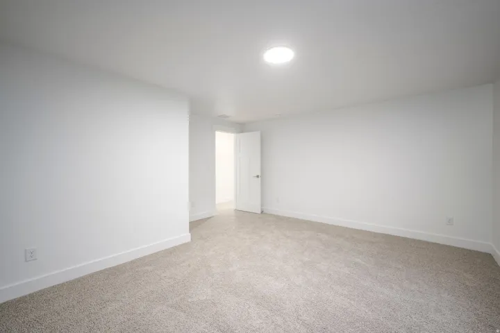 Spacious room featuring neutral carpeting, white walls, and a recessed ceiling light