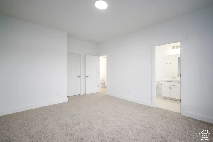 Carpeted interior space featuring white walls and baseboards