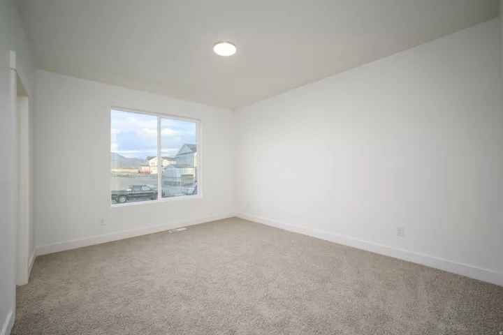 Light-filled interior space featuring a large window, neutral carpet, white walls, and a ceiling-mounted light fixture