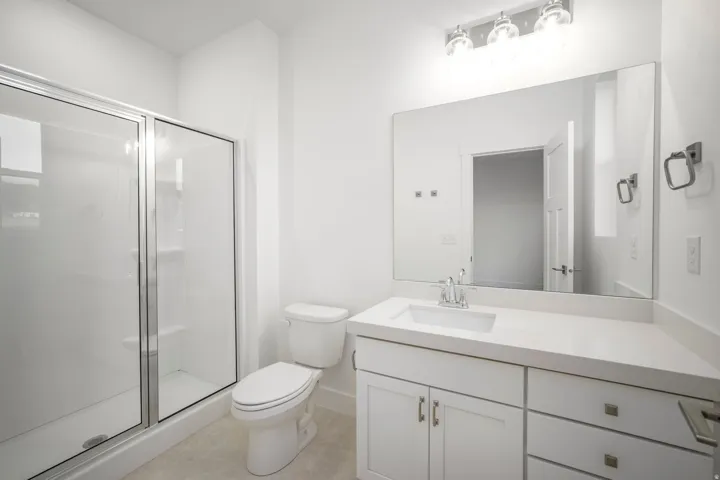 White vanity with a rectangular undermount sink, a chrome faucet, and a light-toned countertop