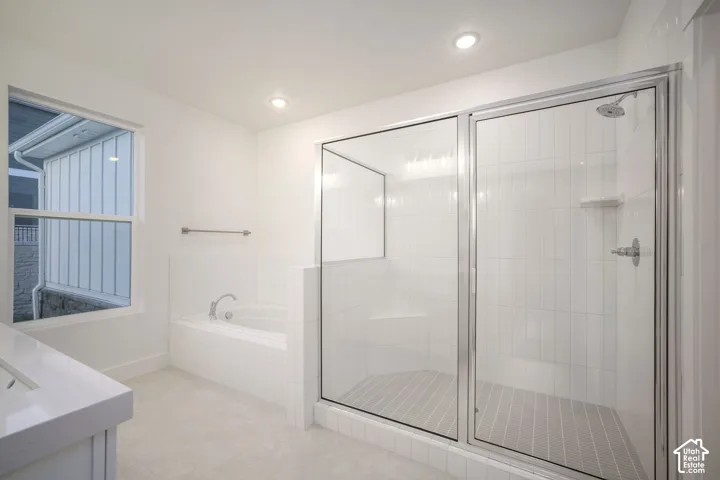 Spacious bathroom featuring a glass-enclosed shower with vertical tile, a built-in shower bench, and a corner soaking tub