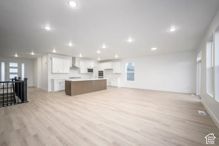 Open-concept living area featuring light wood-finish flooring, recessed lighting, and white walls