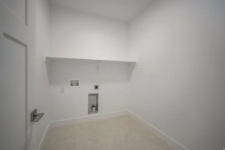 Dedicated utility space featuring a single floating shelf, durable tile flooring, and crisp white walls