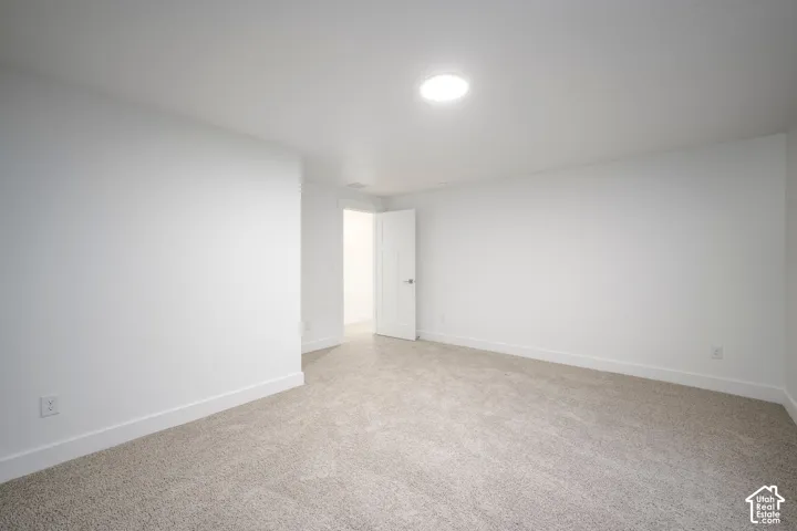 Spacious room featuring neutral carpeting, white walls, and a recessed ceiling light