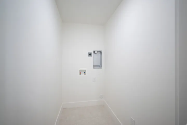 Dedicated utility space featuring light-toned carpeting, white walls, and a ceiling-mounted light fixture