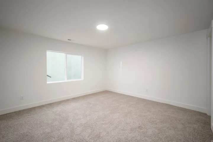 Bright room featuring a single window, recessed ceiling light, white walls, and neutral-toned carpeting