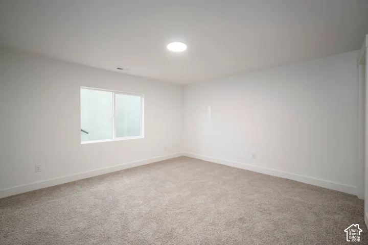 Bright room featuring a single window, recessed ceiling light, white walls, and neutral-toned carpeting