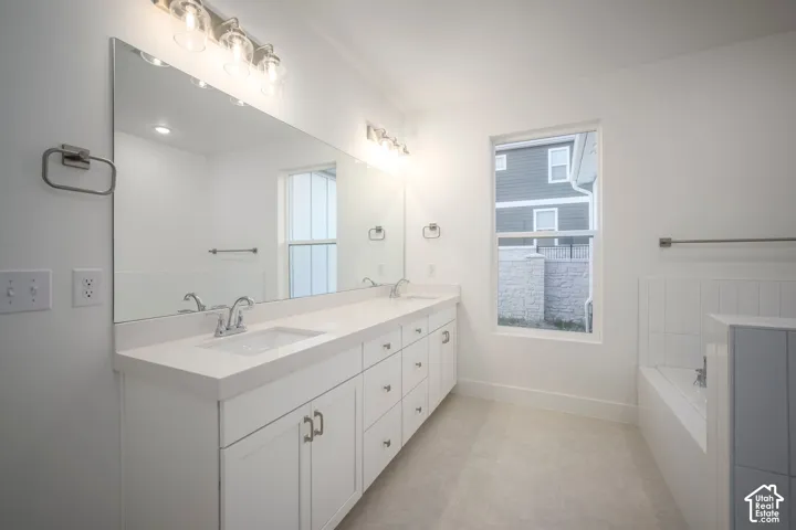 Contemporary bathroom featuring a double vanity with white cabinetry, integrated sinks, a large mirror, and overhead vanity lighting