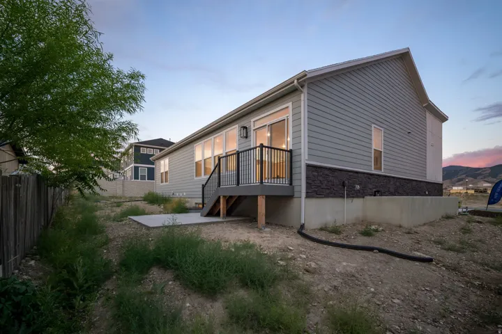 Rear exterior with a composite deck, black metal railings, and a concrete patio