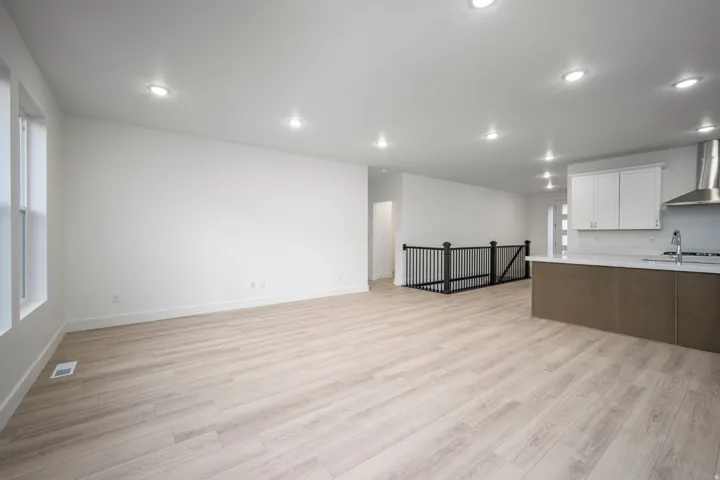 Expansive interior featuring wood-finish flooring, recessed lighting, and a kitchen island with integrated sink