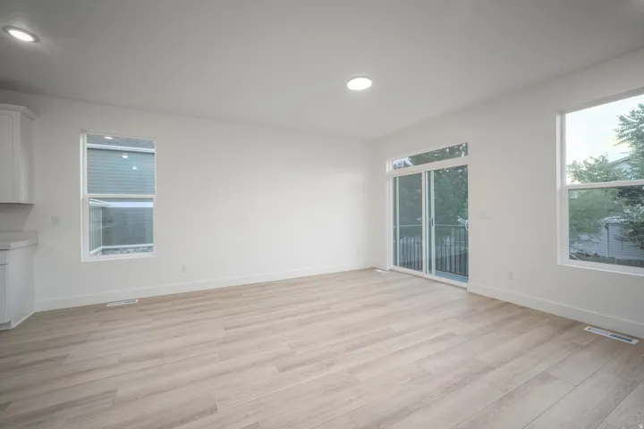 Bright open-concept living area with light wood-finish flooring, recessed lighting, and white walls