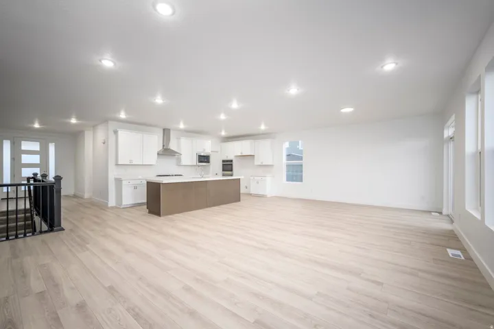 Open-concept living area featuring light wood-finish flooring, recessed lighting, and white walls