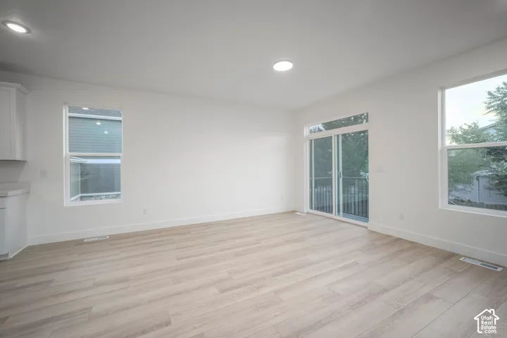 Bright open-concept living area with light wood-finish flooring, recessed lighting, and white walls