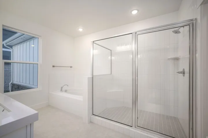 Spacious bathroom featuring a glass-enclosed shower with vertical tile, a built-in shower bench, and a corner soaking tub