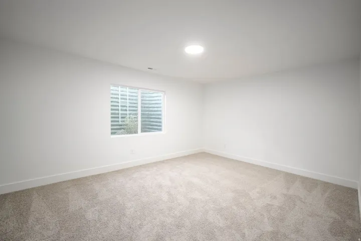 Carpeted room with white walls, a single window, recessed lighting, and white baseboards