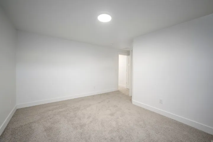 Carpeted room with white walls, white baseboards, and a circular ceiling light fixture